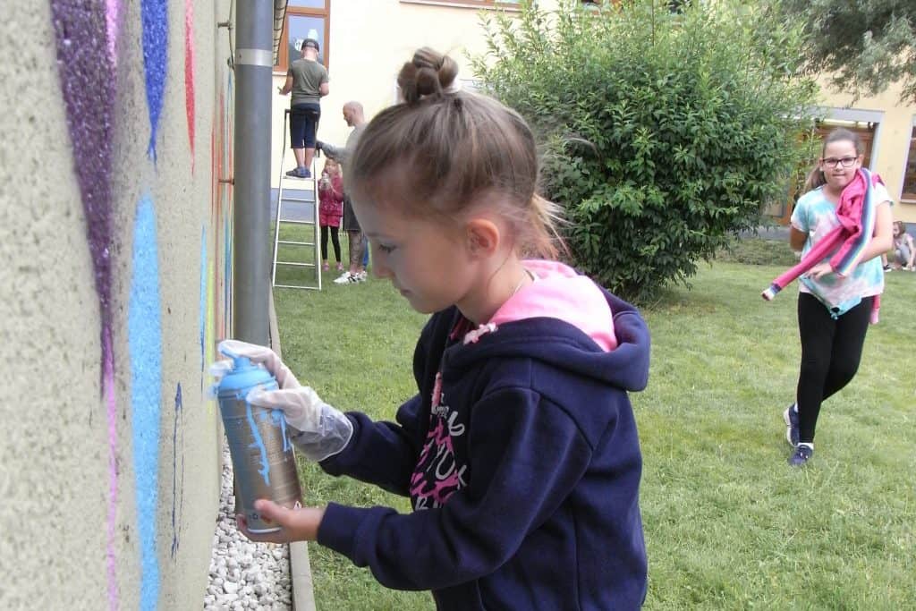 Kinder sprühen mit Dosen farbenfrohe Graffiti-Kunstwerke 