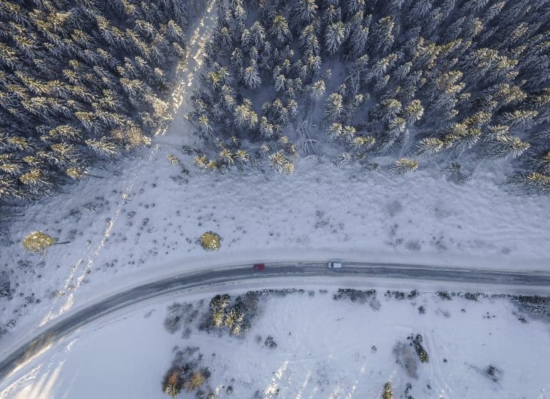 schneebedeckte Landstraße mit Fahrzeug