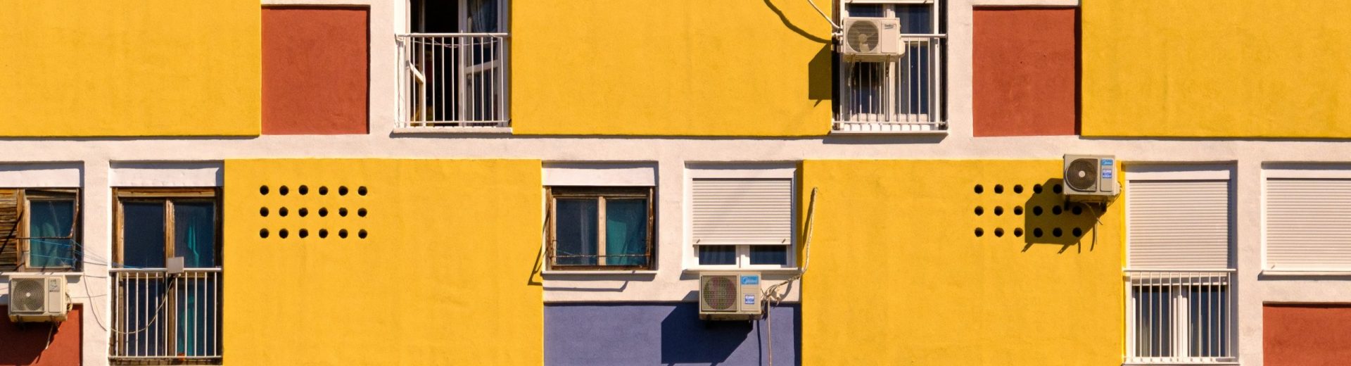 gelbes Haus mit Klimaanlagen an den Fenstern