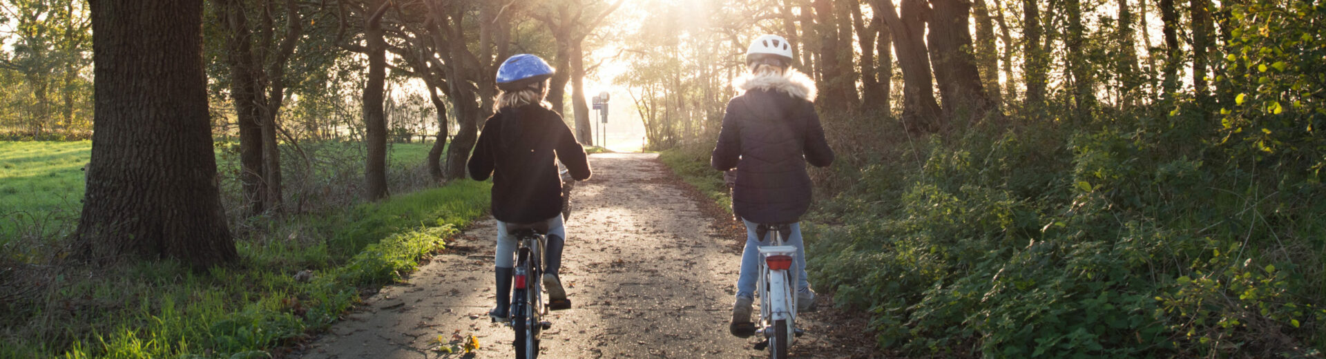 zwei Mädchen fahren auf einem Waldweg Fahrrad