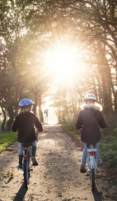 zwei Mädchen fahren auf einem Waldweg Fahrrad