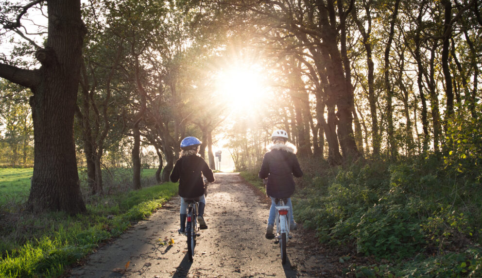 zwei Mädchen fahren auf einem Waldweg Fahrrad