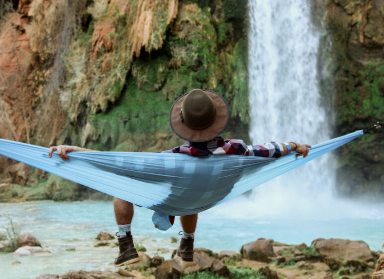 Mann liegt auf einer Hängematte vor einem Wasserfall