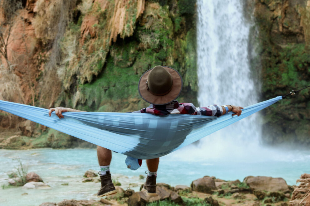 Mann liegt auf einer Hängematte vor einem Wasserfall