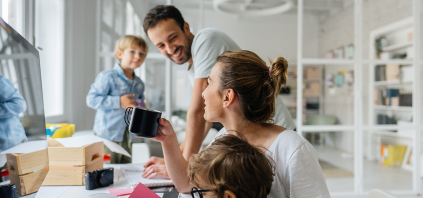 eine junge Familie mit zwei Kindern vor einem Monitor sitzend