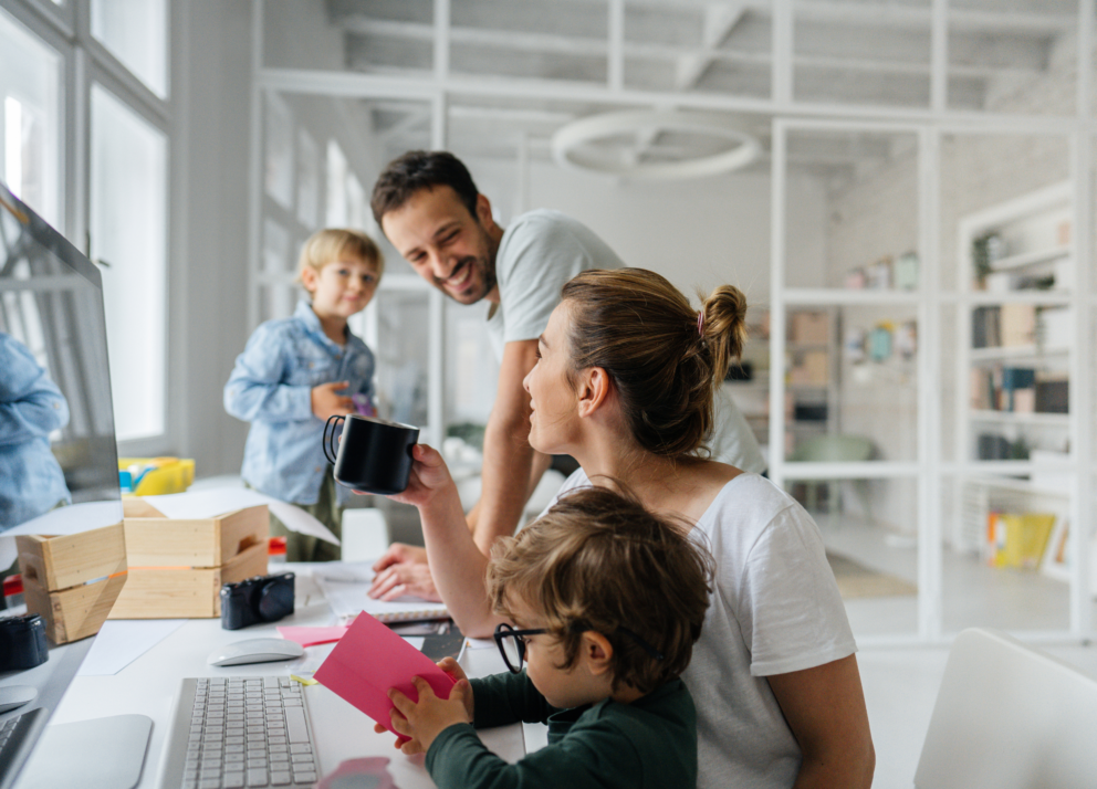 eine junge Familie mit zwei Kindern vor einem Monitor sitzend