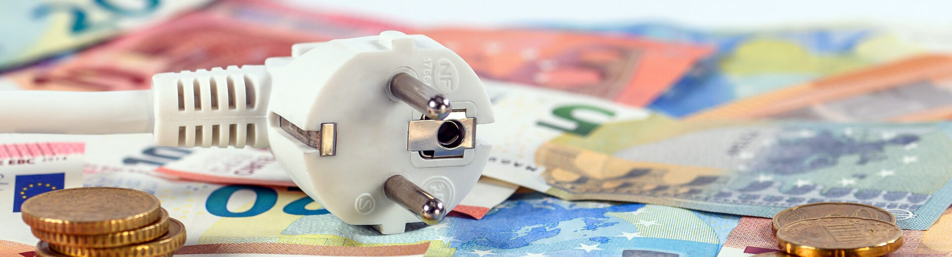 Ein Stecker liegt auf Geldscheinen und Münzen