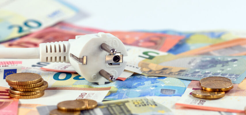 Ein Stecker liegt auf Geldscheinen und Münzen