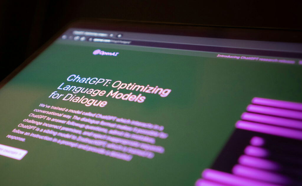 Website mit grünem Hintergrund und großem Titel "ChatGPT: Optimizing Language Models for Dialogue" auf einem schräg fotografierten Bildschirm, rechter Rand zeigt violette Balken.